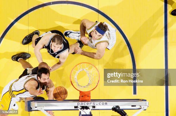 Jeff Foster of the Indiana Pacers puts up a bank shot as teammate Scot Pollard and Rasho Nesterovic of the San Antonio Spurs look on during their NBA...