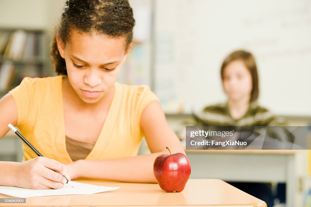 Young Student Sits At Her Desk With An Apple