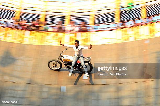 An Indian artist performs a motorcycle stunt show called 'Death well' during a circus, at Annual Magh Mela ,in Allahabad on February 19,2016.