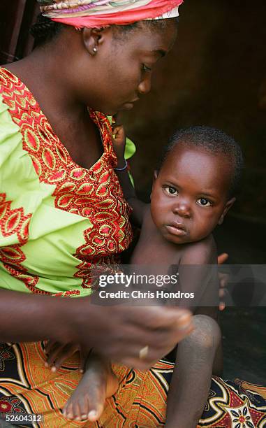 Hadeeza Aminu, the wife of a polio sufferer tends to her son, Umar, 2 1/2, who also has polio and can only crawl since one of his legs has been...