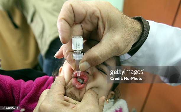 Palestinian health worker administrates polio-vaccine drops to a child during five days of an anti-polio campaign, in Gaza City on December 09, 2013....