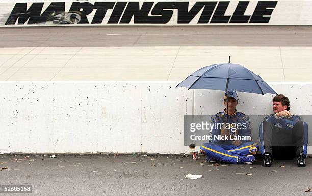 Michael Waltrip driver of the NAPA Auto Parts Chevrolet sits with Randy LaJoie driver of the Mach 1 Racing Chevrolet during a short rain delay during...