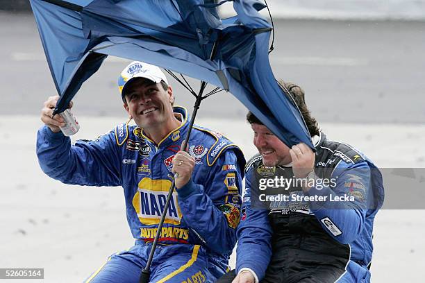 Michael Waltrip, driver of the NAPA Auto Parts Chevrolet, and Randy LaJoie, driver of the Mach 1 Racing Chevrolet, try to save their umbrella during...