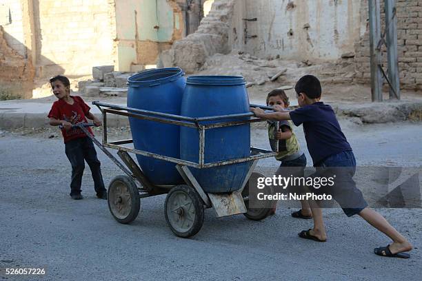 Eastern Ghouta, Syria, on july 13, 2015. Children running wagon put them water filled tank of water manual plunger The suffering of parents and...