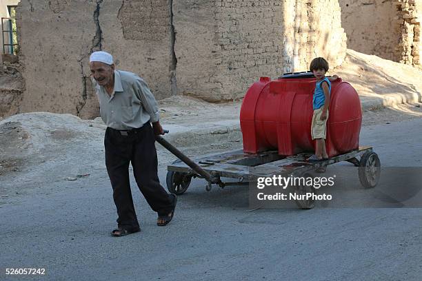 Eastern Ghouta, Syria, on july 13, 2015. An old man dragging wagon put them water filled tank of water manual plunger The suffering of parents and...