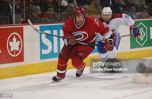 Defenseman Aaron Ward of the Carolina Hurricanes skates behind the net while being pressured by right wing Donald Audette of the Montreal Canadiens...