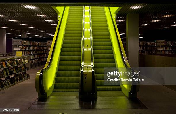 Bright neon yellow escalators connect different levels in Seattle Public Library's central branch, designed by Dutch architect Rem Koolhaas of OMA ....