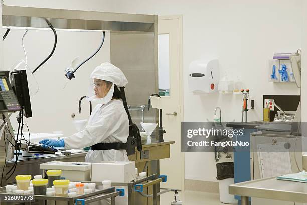 histologist in lab disecting tissue - biohazard symbol stockfoto's en -beelden