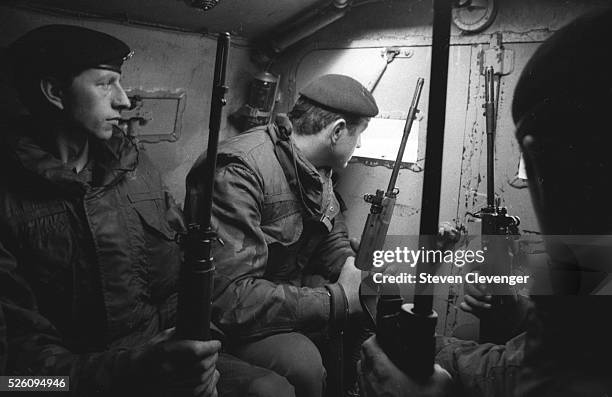 British troopers sit inside an armoured vehicle while on patrol in Belfast. A trooper peers out the rear port of the vehicle watching for anything...