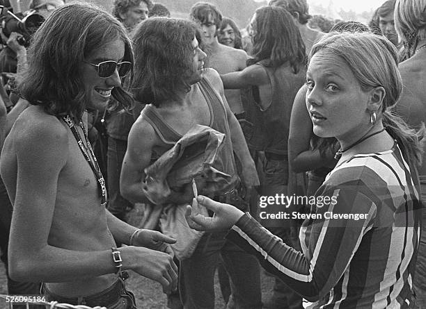 During a Bay Area rock concert two people share what appears to be a marijuana cigarette.