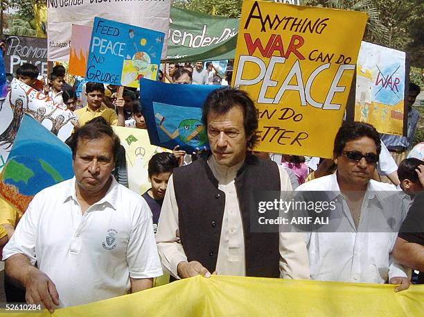 Pakistani cricketer turned politician Imran Khan and film director Syed Noor hold a banner during a walk demonstrating against violence towards women...