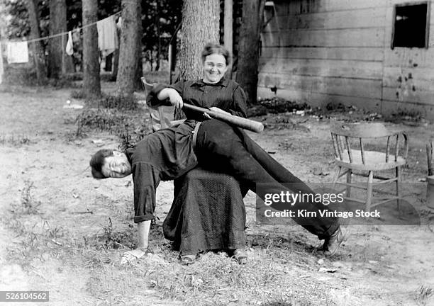 Woman spanks man with baseball bat playfully, ca. 1905 News Photo