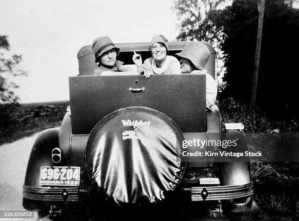 Three flappers pose in the jump seat of a Whippet car, ca. 1928