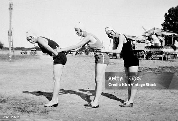 Three swimming suited women pose, ca. 1919