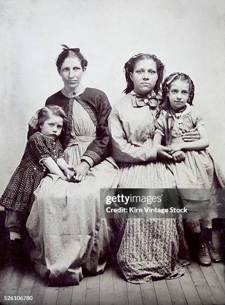 Two mothers pose with their daughters for a formal tintype portrait, ca. 1880