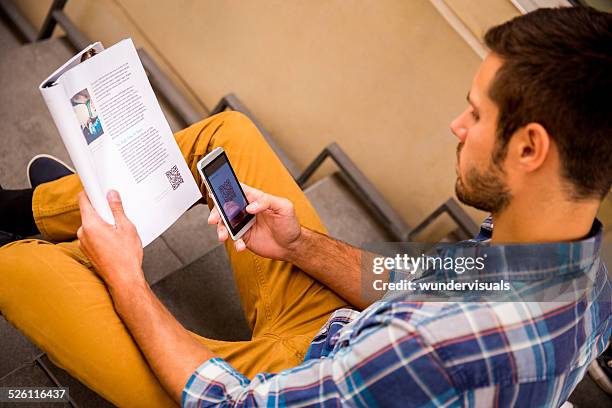 man scanning qr code with smartphone - man holding book stock pictures, royalty-free photos & images