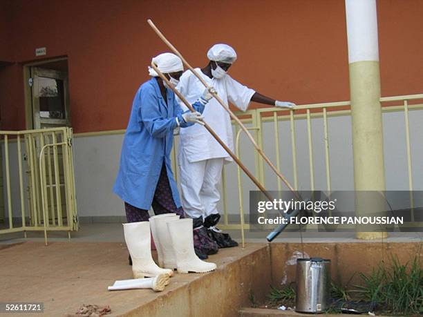 Mask-clad health workers do some cleaning, outside an emergency ward in an hospital, 10 April 2005 in Uige, about 300km north of the capital, Luanda,...