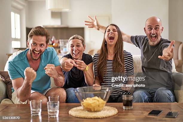 happy soccer fans cheering their team on tv - celebrate living stockfoto's en -beelden