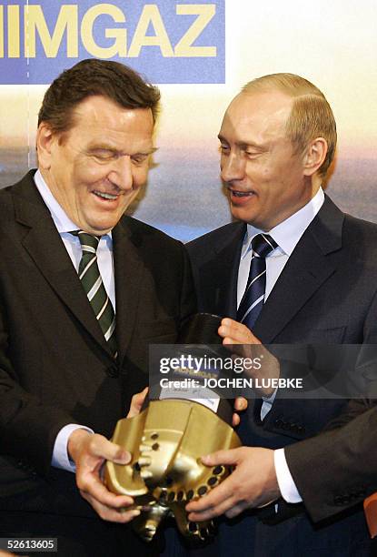 German Chancellor Gerhard Schroeder and Russian President Vladimir Putin present a drill head as they visit the Hanover Fair for industrial...