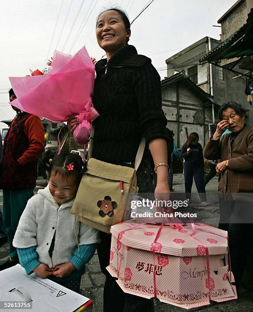 Resident carries flowers and a cake presented by government officials to celebrate the moving, while they begin to move out the Bailianjing Area at...