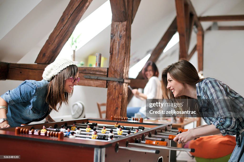Happy young  office workers playing table football