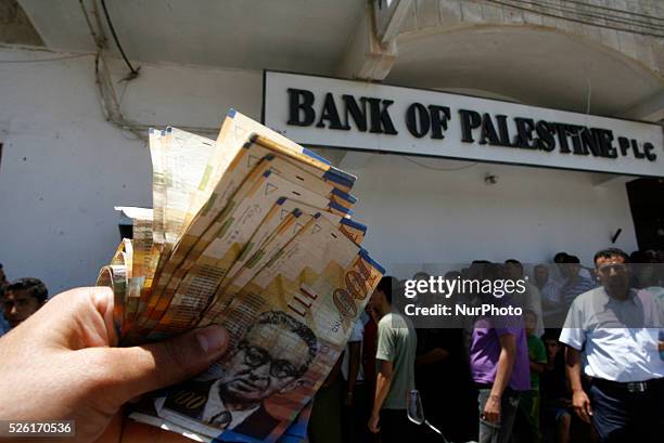 Employees of the Palestinian Authority shows the money he withdrew from an ATM, in the Rafah in the southern Gaza Strip on June 11, 2014. Palestinian...