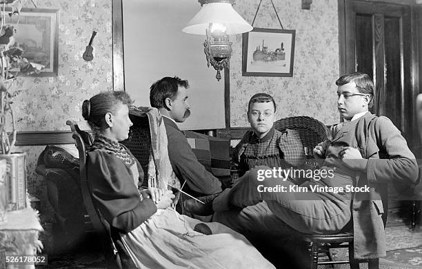 Mom and Dad hold really still with their teenage children for a photographic portrait in the early 20th century.
