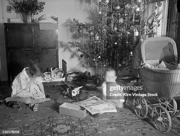 Brother and sister under the tree with their presents on Christmas tree.