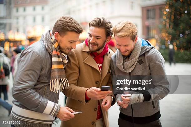 amigos de compartir información sobre sus smartphones. - group of friends walking along street fotografías e imágenes de stock