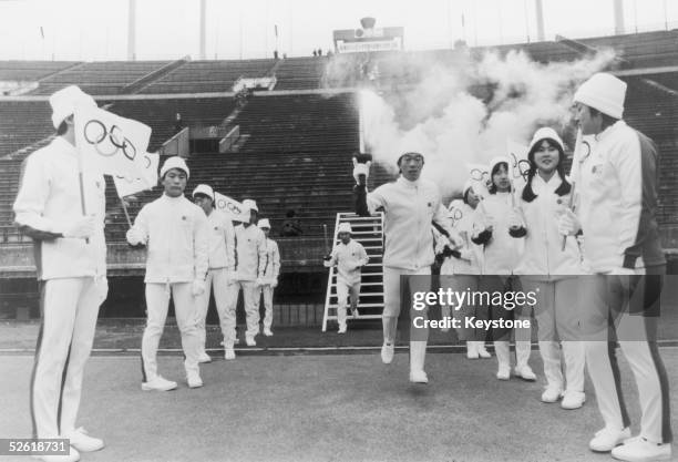 Japanese ice skater Tomoo Kurosawa arrives at the Olympic Stadium in Tokyo carrying the Olympic Flame during a rehearsal for the Sapporo Winter...