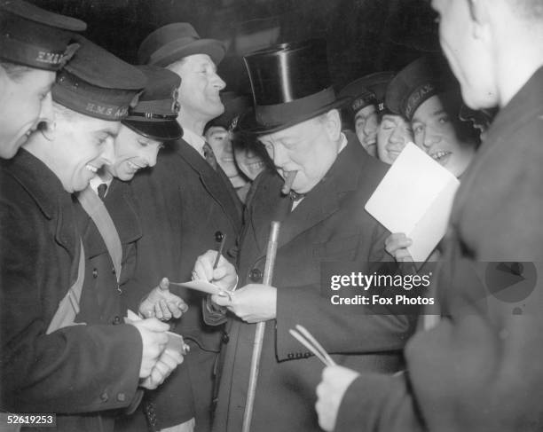 British Prime Minister Winston Churchill signs autographs for men of H.M.S. Ajax and H.M.S. Exeter, 1940.