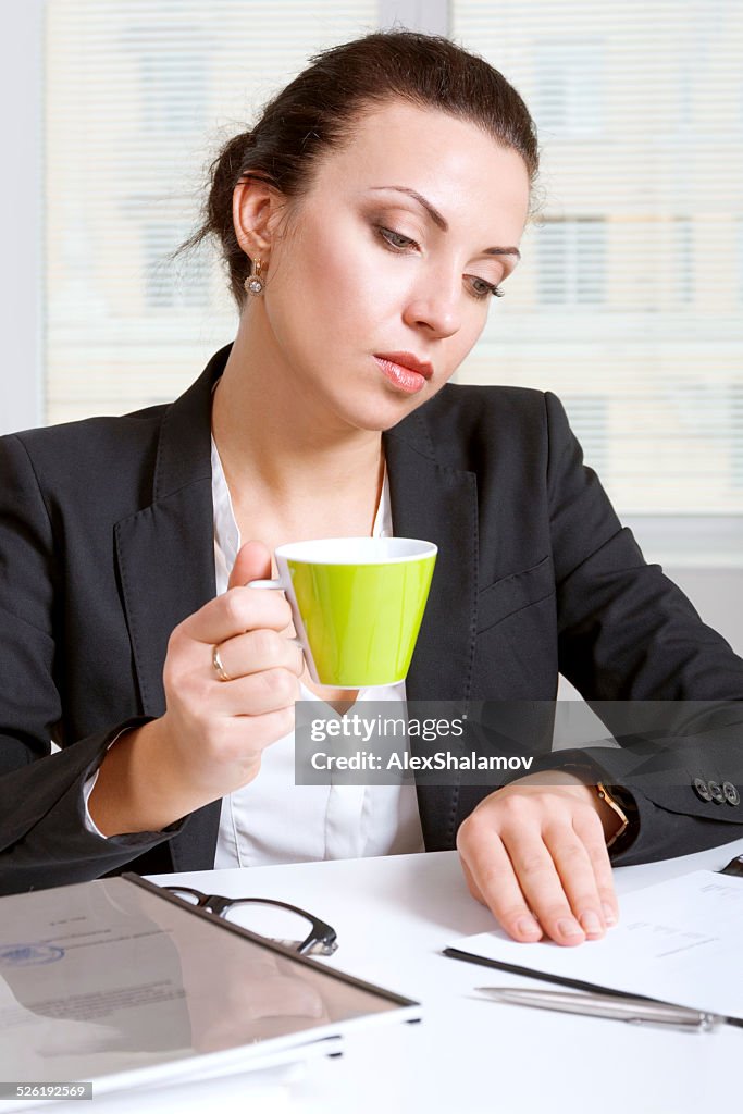 Girl in drink coffee looking documents