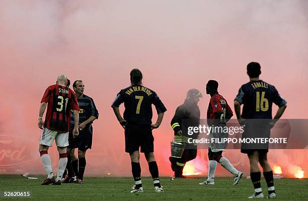Firebrigader collects fireworks as Inter-Milan' and AC Milan's players wait for smoke to clear after fans threw fireworks onto the field during the...