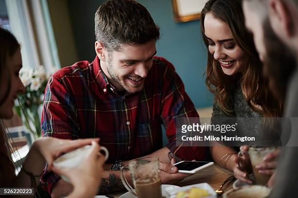 group of friends using smart phone in cafe - social mobile stock pictures, royalty-free photos & images