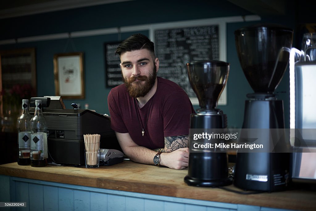 Young male barista in urban cafe