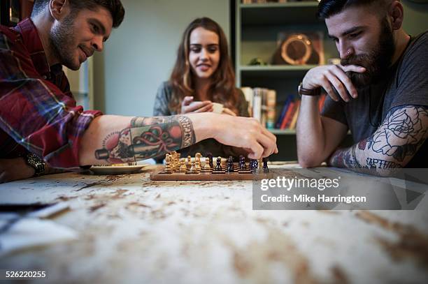 young tattooed males playing chess - game night leisure activity fotografías e imágenes de stock
