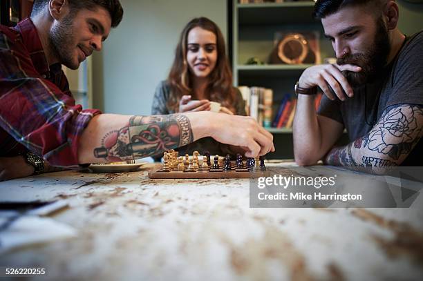 young tattooed males playing chess - board games stock pictures, royalty-free photos & images