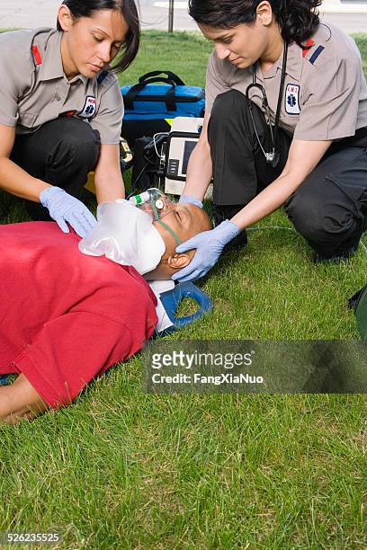paramedics fijación de collarín médico con paciente sobre hierba - collarín médico fotografías e imágenes de stock