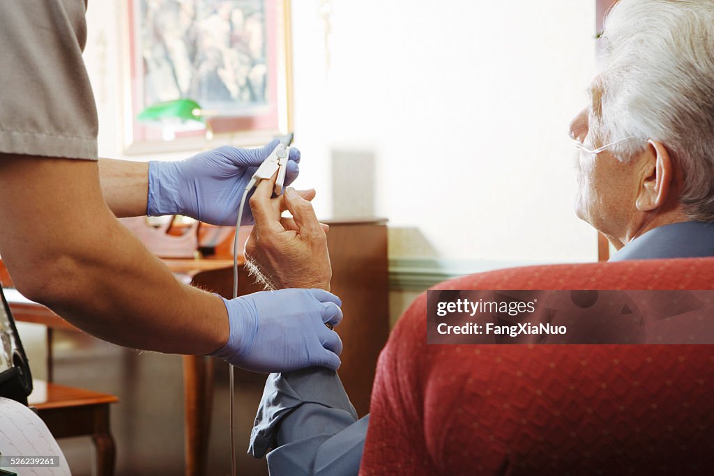 Paramedic attaching pulse monitor to senior man's finger