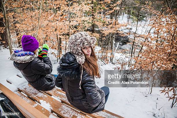 zwei mädchen sitzt auf der bank im winter forest - pocono stock-fotos und bilder