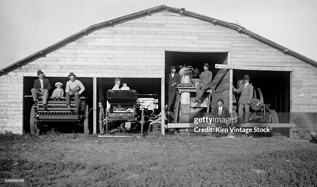 The family poses on barn equipment, ca. 1910
