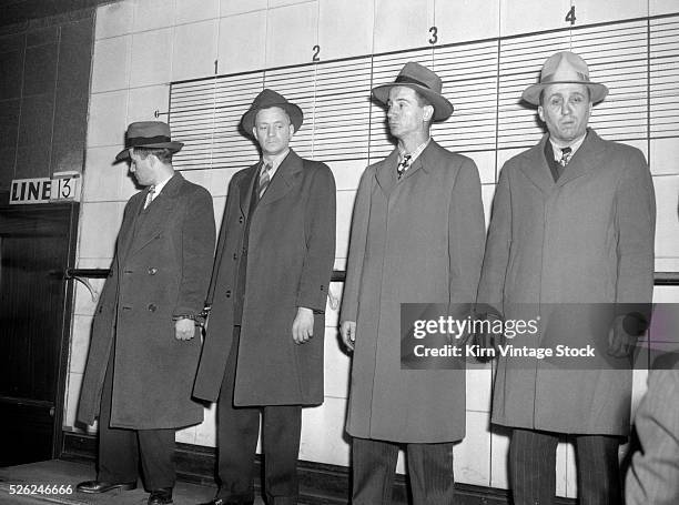 Four men stand in a police line-up for a witness to look over.