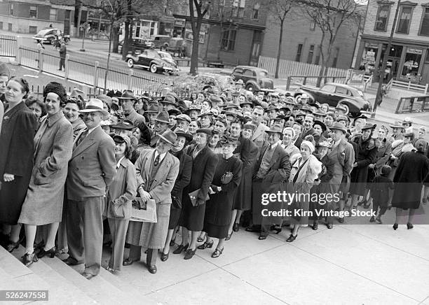 People wait in line for their turn to register for and receive coupons for rationed goods during World War Two.