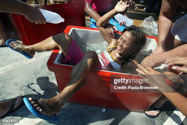 Thai woman gets thrown into a cooler filled with ice water during the celebration of Songkran, the Thai New year April 13, 2005 in the Tsunami...