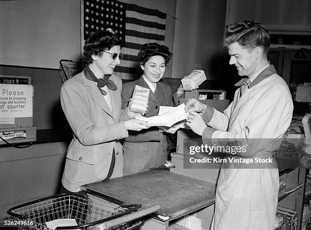 Two women buy rationed sugar from a grocery clerk using their War Coupons in Chicago during World War Two.