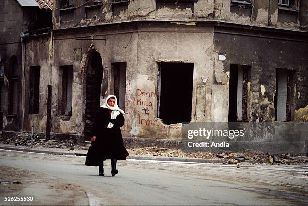 War in the former Yugoslavia. February 1994, the capital city of Bosnia-Herzegovina during the siege of Sarajevo. A woman crossing the rubbles of the...