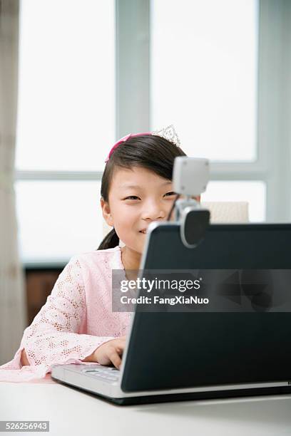 girl (8-9) using laptop and looking into webcam, smiling - china middle class stock pictures, royalty-free photos & images