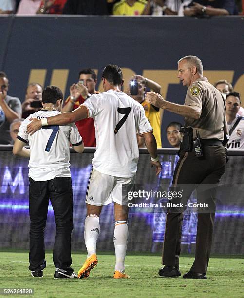 Real Madrid player Cristiano Ronaldo and fan that gave him a hug are greeted by a police officer during the Championship match between Chelsea FC and...