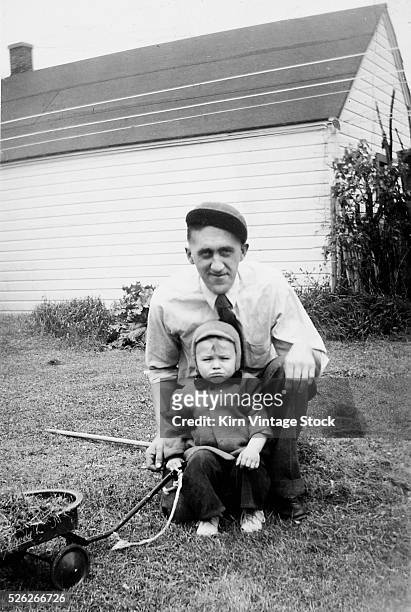 Father and son pull a wagon in backyard, ca. 1946