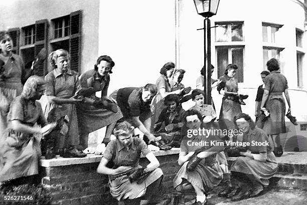 Maids gather together to clean and polish shoes outside in Germany.